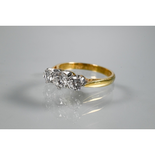 231 - A three-stone diamond ring, the graduated diamonds claw set in platinum, with 18ct yellow gold shank... 