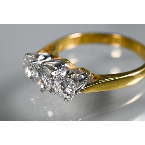 231 - A three-stone diamond ring, the graduated diamonds claw set in platinum, with 18ct yellow gold shank... 