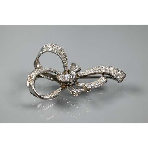 247 - A diamond brooch, the white metal set overall with mixed cut diamonds in the style of a loosely-tied... 