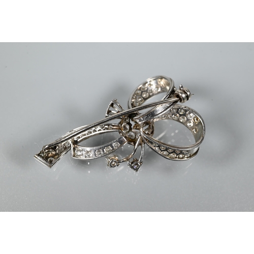 247 - A diamond brooch, the white metal set overall with mixed cut diamonds in the style of a loosely-tied... 