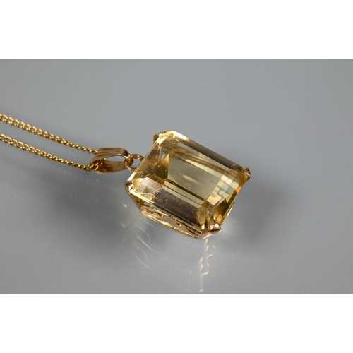 301 - A rectangular baguette-cut yellow topaz pendant on yellow metal chain, the topaz approx 1.3 x 1.1 cm