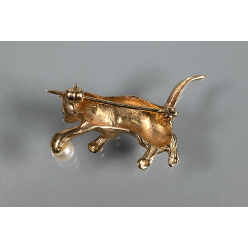 322 - A 9ct yellow gold brooch in the form of a cat playing with a pearl in the form of a ball, with emera... 