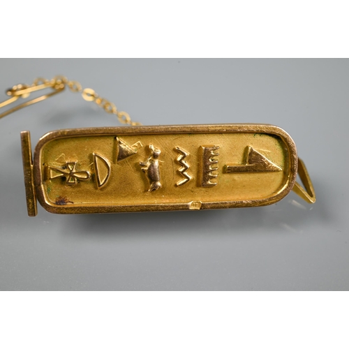 325 - A yellow metal Egyptian cartouche with hieroglyphics in the form of a brooch, safety chain attached,... 