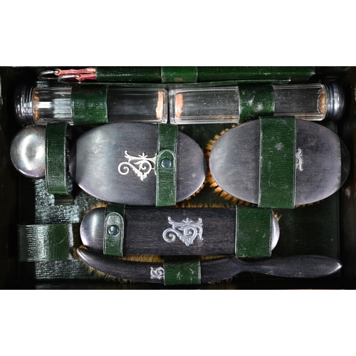 36 - A leather toiletry case, the green Morocco interior fitted with ebony brushes with unmarked silver m... 