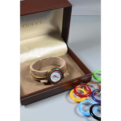 423 - A contemporary Gucci ladies wristwatch, gilt case and band with interchangeable coloured acrylic bez... 