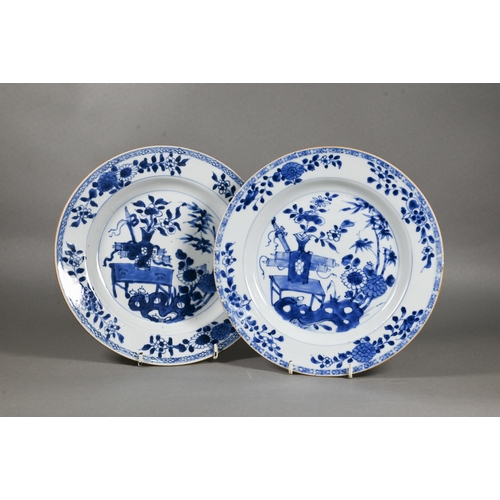 482 - A pair of 18th century Chinese blue and white plates, painted with a vase of flowers on a table in a... 