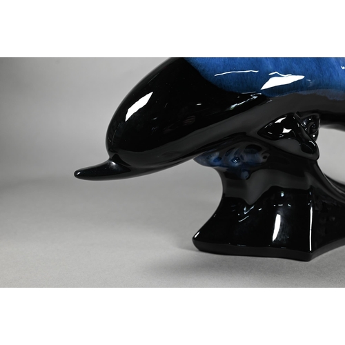 65 - A large pottery model of a leaping dolphin, on naturalistic wave base, 23 x 41 cm