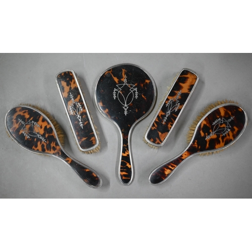 97 - A silver, tortoiseshell and piqué-work five-piece brush set with hand-mirror, Birmingham 1922, to/w ... 