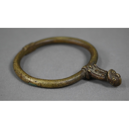 1075 - A West African bronze bangle, surmounted by a seated man, 11.5 x 9 cm