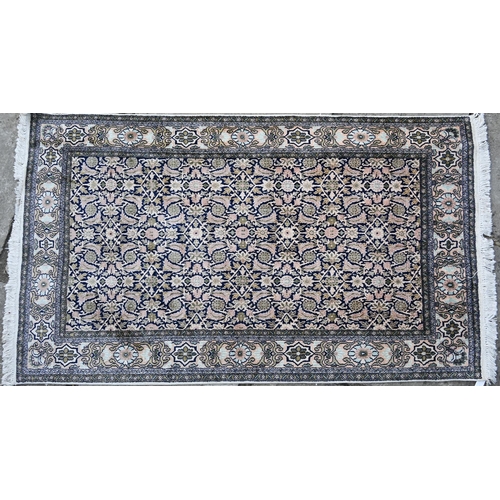 803 - An old silk Hereke rug, the field of repeating geometric flower heads on dark blue ground, 157 cm x ... 