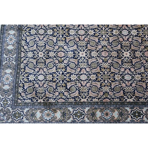 803 - An old silk Hereke rug, the field of repeating geometric flower heads on dark blue ground, 157 cm x ... 