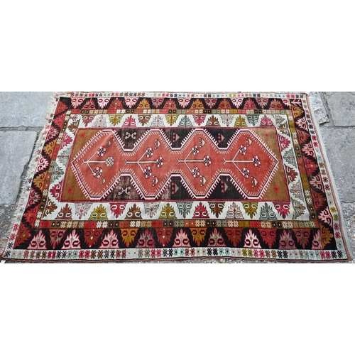 808 - An antique Kazak pale red ground rug, the lozenge pole design within geometric borders, 206 cm x 130... 