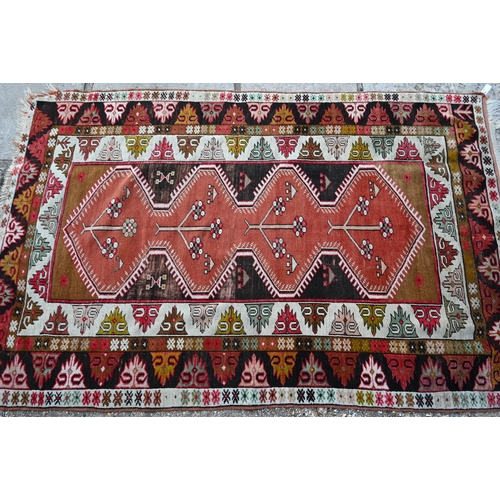 808 - An antique Kazak pale red ground rug, the lozenge pole design within geometric borders, 206 cm x 130... 