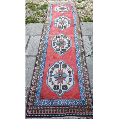 817 - A Turkish Kazak design runner, the four diamond pole design on red ground, 323 cm x 78 cm