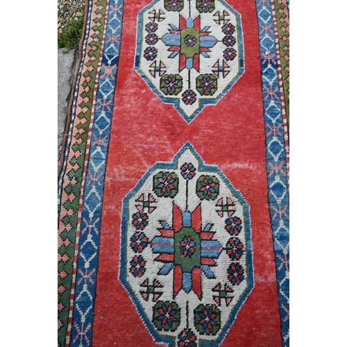 817 - A Turkish Kazak design runner, the four diamond pole design on red ground, 323 cm x 78 cm