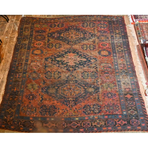 821 - An antique Caucasian Sumak / Soumak carpet, the brown-red ground with geometric guls within wide bor... 