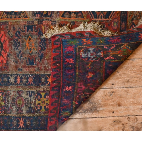 821 - An antique Caucasian Sumak / Soumak carpet, the brown-red ground with geometric guls within wide bor... 