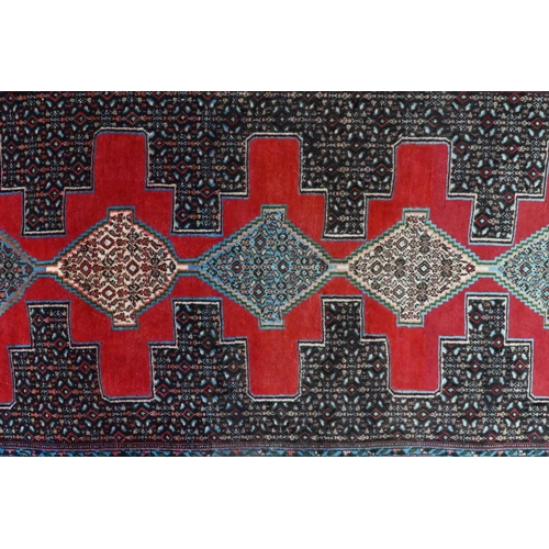 823 - A contemporary North West Persian Senneh runner, the lozenge pole design on red ground, 300 cm x 100... 