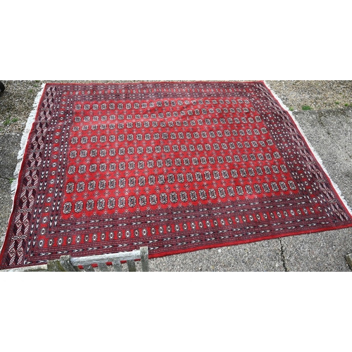 834 - A contemporary Turkoman red ground carpet, the repeating gul design within wide borders, 364 cm x 28... 