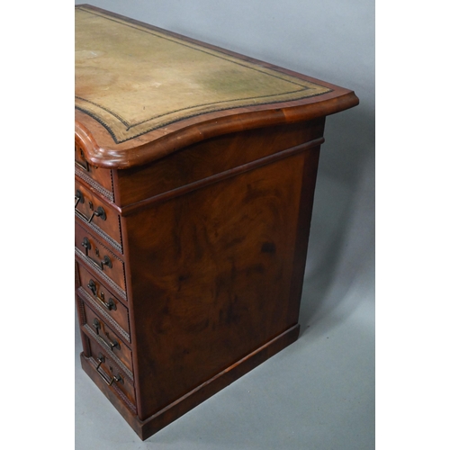 864 - A continental walnut leather topped desk, of inverted serpentine form with an arrangement of thirtee... 