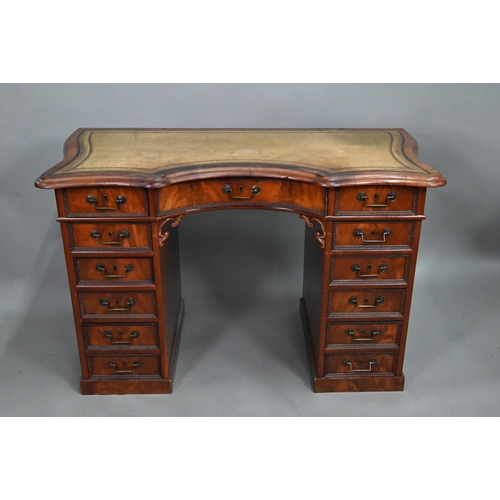 864 - A continental walnut leather topped desk, of inverted serpentine form with an arrangement of thirtee... 