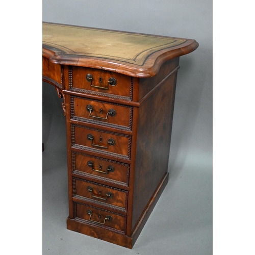 864 - A continental walnut leather topped desk, of inverted serpentine form with an arrangement of thirtee... 