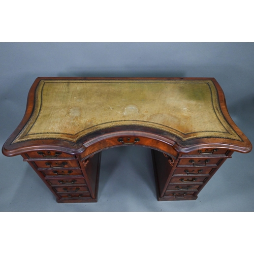 864 - A continental walnut leather topped desk, of inverted serpentine form with an arrangement of thirtee... 