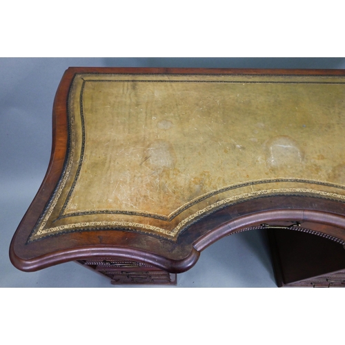 864 - A continental walnut leather topped desk, of inverted serpentine form with an arrangement of thirtee... 