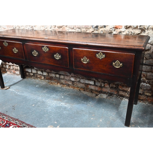 866 - An 18th century oak low dresser, the wide single plank top over three drawers within a shaped apron,... 