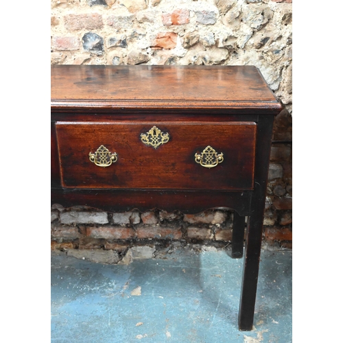 866 - An 18th century oak low dresser, the wide single plank top over three drawers within a shaped apron,... 