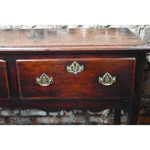 866 - An 18th century oak low dresser, the wide single plank top over three drawers within a shaped apron,... 