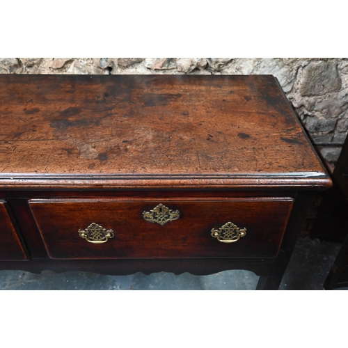 866 - An 18th century oak low dresser, the wide single plank top over three drawers within a shaped apron,... 