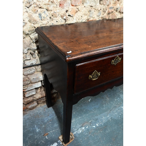 866 - An 18th century oak low dresser, the wide single plank top over three drawers within a shaped apron,... 