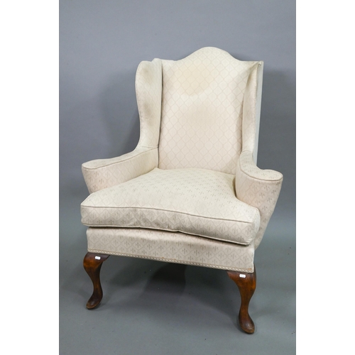 874 - A late 19th century wing armchair in the George II style, with out-swept arms, raised on walnut cabr... 