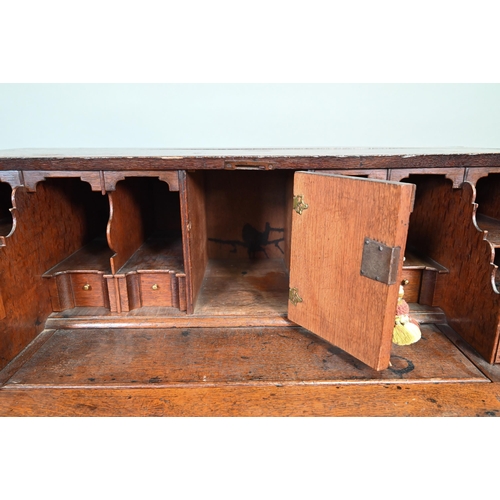 887 - An 18th century oak bureau, the fall enclosing a fitted interior of niches and slide top well over t... 