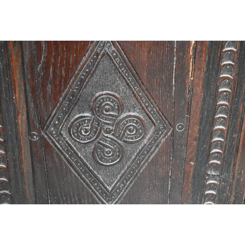 906 - A late 17th century carved oak coffer, the two plank top over a lunette carved frieze and four incis... 