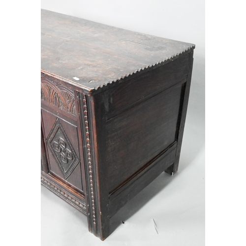 906 - A late 17th century carved oak coffer, the two plank top over a lunette carved frieze and four incis... 