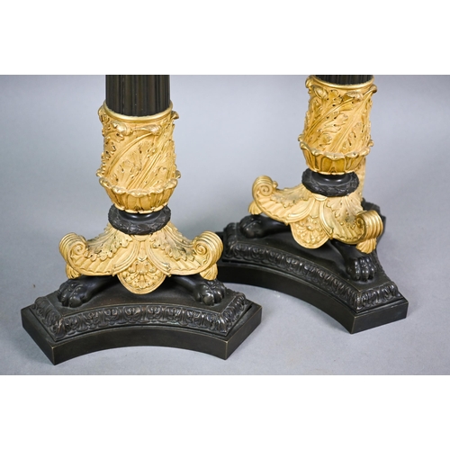 985 - A pair of dark bronzed and gilt metal five candle column candelabra, in the Empire style, raised on ... 