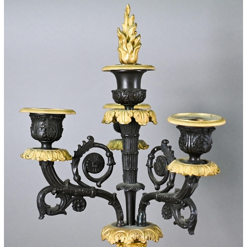 985 - A pair of dark bronzed and gilt metal five candle column candelabra, in the Empire style, raised on ... 