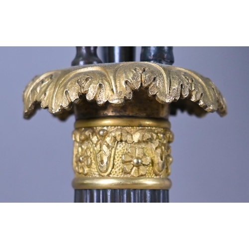 985 - A pair of dark bronzed and gilt metal five candle column candelabra, in the Empire style, raised on ... 