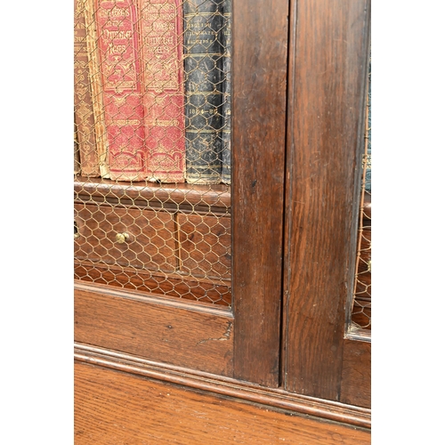 266 - An antique oak cabinet bookcase, the lattice wire panelled doors enclosing shelves and small drawers... 