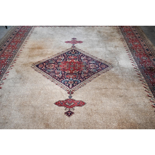 384 - A large Turkish Isparta camel ground carpet, with central diamond medallion and red border, 387 x 27... 