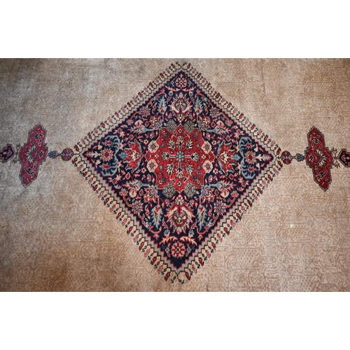 384 - A large Turkish Isparta camel ground carpet, with central diamond medallion and red border, 387 x 27... 