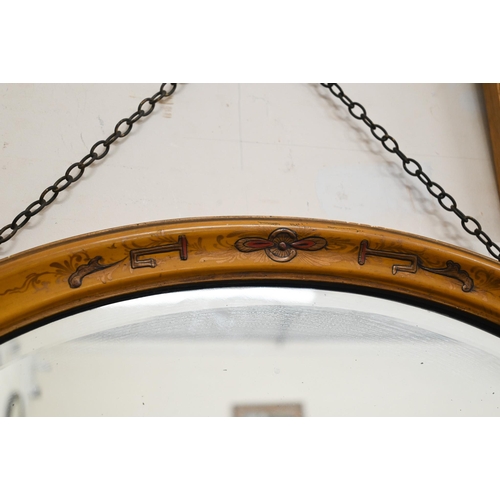 393 - A bevelled oval wall mirror in Japanned polychrome frame, 64 cm wide x 48 cm high