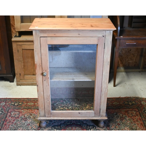 216 - A pine cabinet with single glazed door, raised on turned feet, 73 cm x 36 cm x 107 cm h