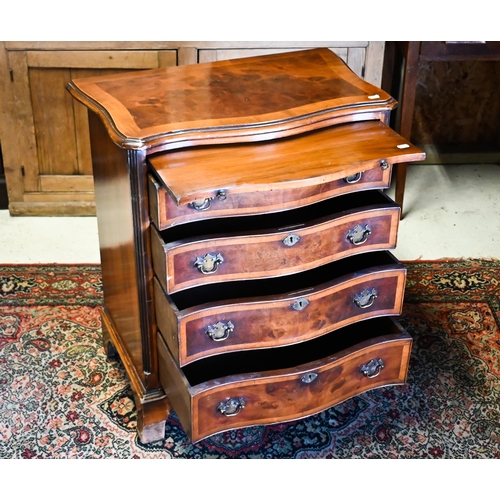 251 - A reproduction cross-banded walnut small serpentine form four drawer chest, with brush slide, 63 cm ... 