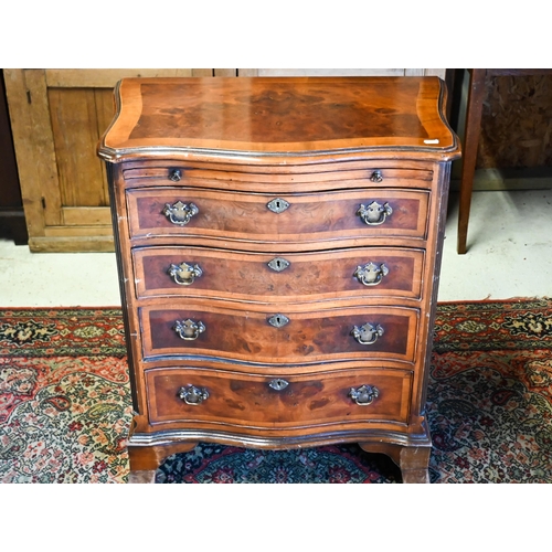 251 - A reproduction cross-banded walnut small serpentine form four drawer chest, with brush slide, 63 cm ... 