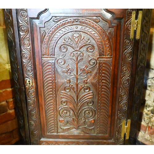 447 - An antique profusely carved oak hanging corner cupboard, the interior with shelves and two drawers, ... 