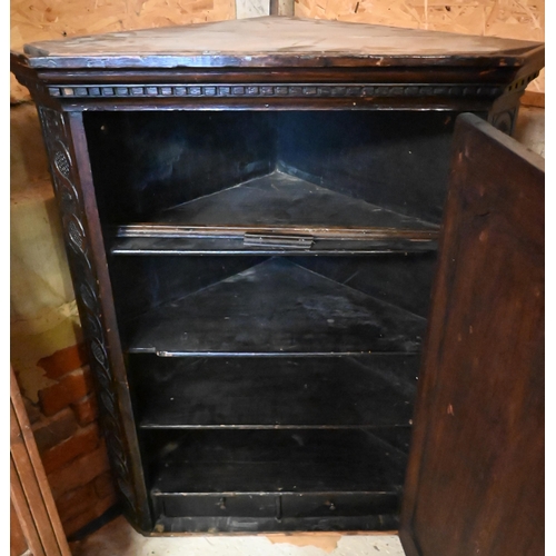 447 - An antique profusely carved oak hanging corner cupboard, the interior with shelves and two drawers, ... 