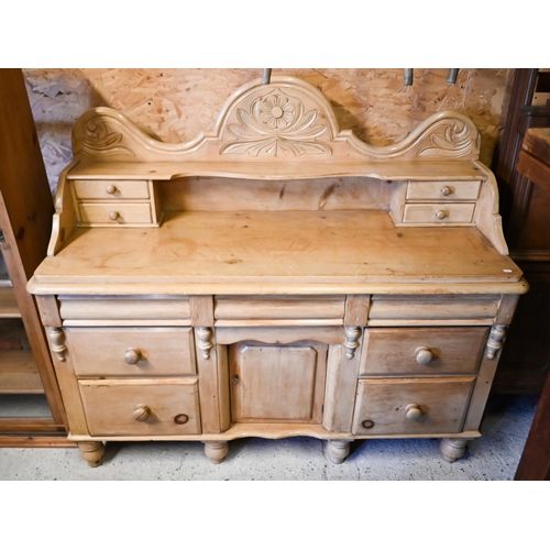 448 - An antique stripped pine gallery backed sideboard, with an arrangement of seven drawers around a cen... 